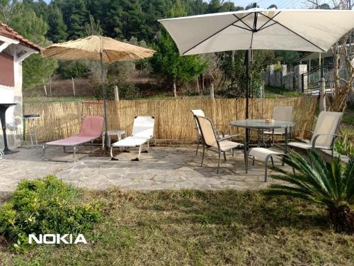 a patio with chairs and tables and an umbrella at Alex house with garden in kallithea halkidiki in Kallithea Halkidikis