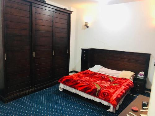 a bedroom with a bed with a red blanket and wooden doors at El Fouad house in Luxor