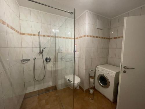 een badkamer met een douche, een toilet en een wasmachine bij Karo`s Apartment in Mittersill