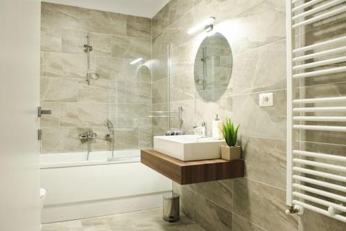 ティミショアラにあるAlternativ 1 Residenceの洗面台、浴槽、鏡のあるバスルーム