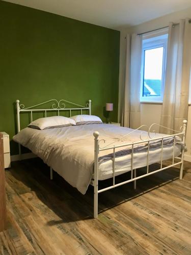 a bed in a bedroom with a green wall at 27 William Jessop Way Bristol BS13 0RL in Whitchurch