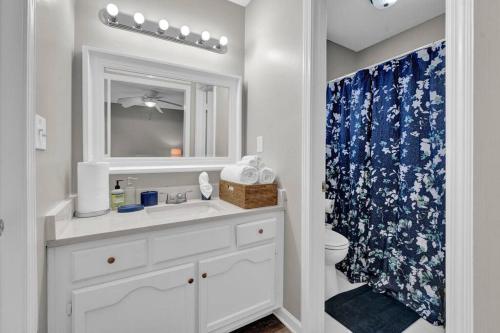 La salle de bains est pourvue d'un lavabo, de toilettes et d'un miroir. dans l'établissement Glamorous 3BR 2BA house w/ large fenced backyard, à Memphis