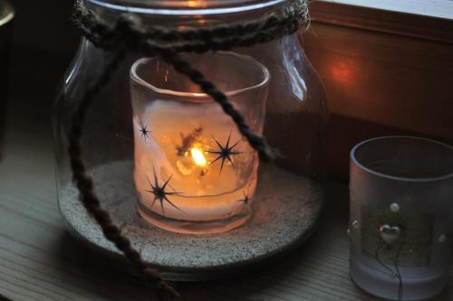 a candle in a glass jar on a table with a cup at Hotel Chesa Staila in La Punt-Chamues-ch