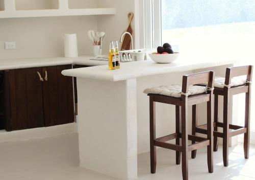 a kitchen with a white counter and two stools at Puerto Bianco Private Residence Collection in Copala