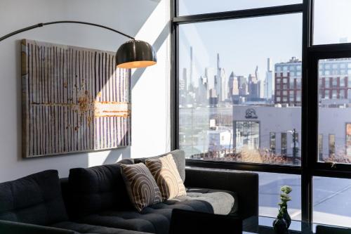 a living room with a couch and a large window at Dharma Home Suites Hoboken in Hoboken
