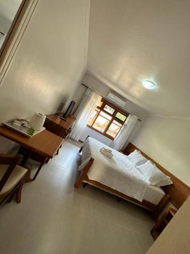 a room with two beds and a desk and a window at Pousada Villa Verde in Canela