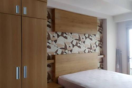 Schlafzimmer mit einem Bett mit einem Kopfteil aus Holz in der Unterkunft Apartemen M Square 23m2 Jl. Cibaduyut No. 142 in Bandung