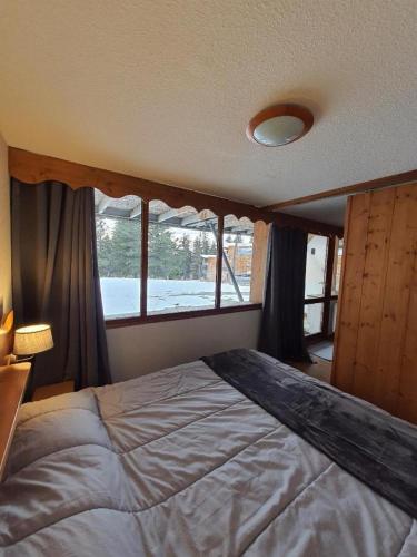 une chambre avec un grand lit et une fenêtre dans l'établissement Chamrousse 1700 - Asters A03 (Rez de Jardin, Terrasse plein sud), à Chamrousse