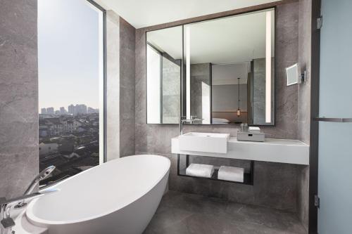 a bathroom with a tub and a sink and a mirror at AC Hotel by Marriott Suzhou China in Suzhou