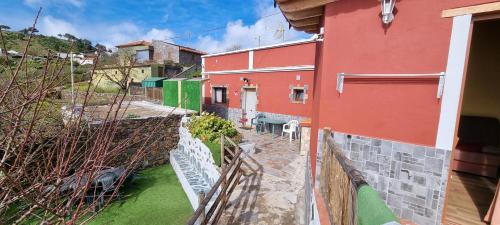 a red building with a fence next to a yard at Casa rural meridiano in El Pinar del Hierro