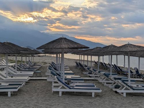 a row of lounge chairs and umbrellas on a beach at Costa Petra - Luxury Seaside Cottage with Garden - Vacation House for families in Greece in Néa Meságkala