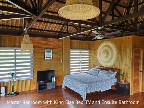 a bedroom with a bed and a television in it at Luxury Bahay Kubo in a Farm Near Tagaytay in Tagaytay