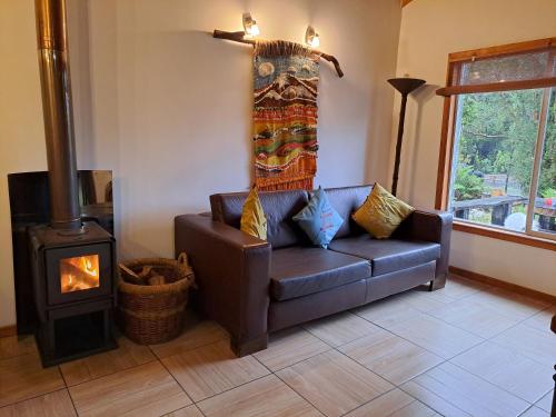 a living room with a leather couch and a wood stove at Cabañas Los Volcanes Ensenada Puerto Varas in Ensenada