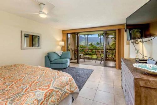 a bedroom with a bed and a television and a balcony at Hanalei Bay Resort BaliHi in Princeville