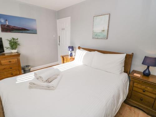 Un dormitorio con una cama blanca con una toalla. en Beach House Ty Traeth, en Deganwy