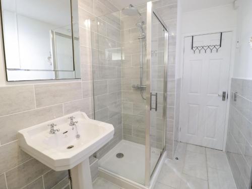 a white bathroom with a sink and a shower at Beach House Ty Traeth in Deganwy