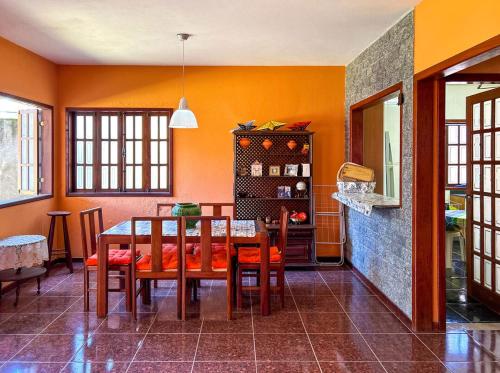 uma sala de jantar com paredes cor de laranja e uma mesa e cadeiras em Incrivel casa com churrasq em Miguel Pereira RJ em Miguel Pereira