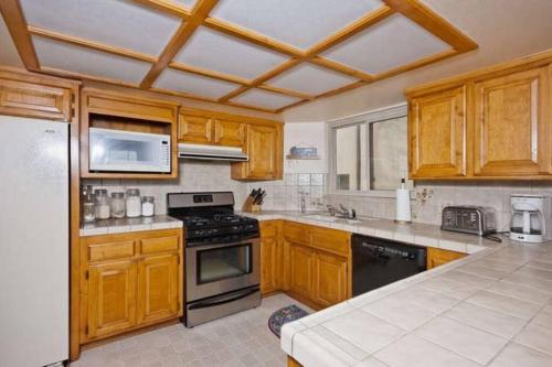 a kitchen with wooden cabinets and a stove top oven at Beautiful Ocean Front Coastal Sunset Beach House in Oxnard