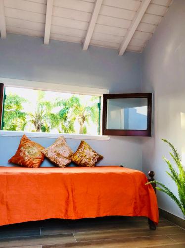 a bedroom with a bed with orange sheets and a window at Chalet Pura Vida in Mar del Plata