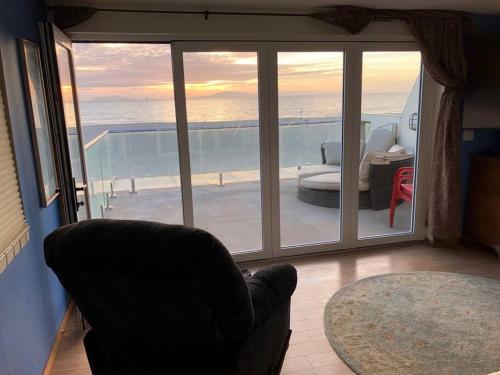 a living room with a chair and a view of the ocean at Beautiful Ocean Front Coastal Sunset Beach House in Oxnard