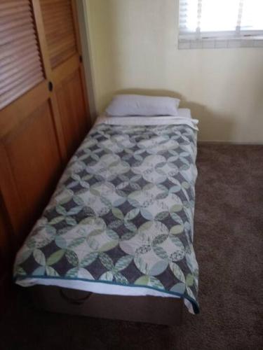 a small bedroom with a bed with a comforter at Beautiful Ocean Front Coastal Sunset Beach House in Oxnard