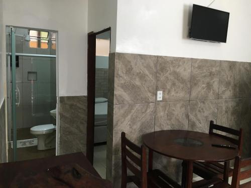 a room with a table and a bathroom with a toilet at Casas do Matteo - 2ª Praia in Morro de São Paulo
