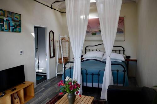 sypialnia z niebieskim łóżkiem z białymi zasłonami w obiekcie Cosy cottage near Hartland Village w mieście Bideford