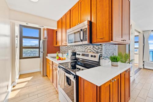 a kitchen with wooden cabinets and a stove top oven at 30FL Great Ocean Views with Lanai, King bed, Parking in Honolulu