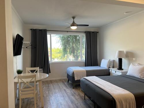 a hotel room with two beds and a table and a window at Unit 19 Maui Ohana Modern Studio in Wailuku