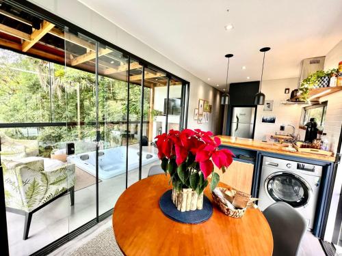 uma cozinha com uma mesa com flores vermelhas em Cabana Romântica na Região dos Lagos em Rio dos Cedros