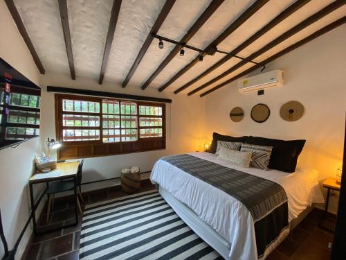 a bedroom with a bed and a desk and windows at Casa Medallo in Medellín