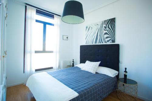 Dormitorio azul y blanco con cama y ventana en Apartament Glorieta Puerta de Toledo en Madrid
