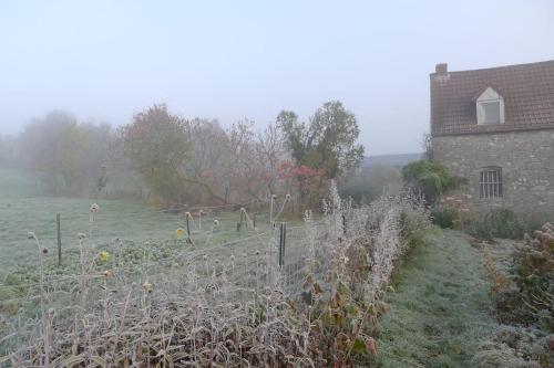 a field with a fence in front of a house at La ferme aux oiseaux B&B in Beaumont