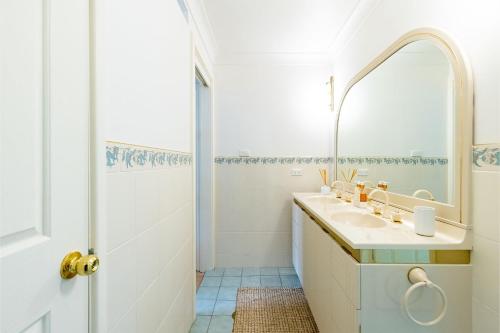 a white bathroom with a sink and a mirror at Anchored at Fingal Bay 80 Marine Drive in Fingal Bay
