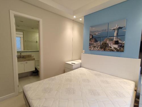 Un dormitorio con una cama blanca y una pintura en la pared en Lanai Apart Hotel, Flat Moderno com Vista Mar no Posto 2 da Barra B1-0031, en Río de Janeiro