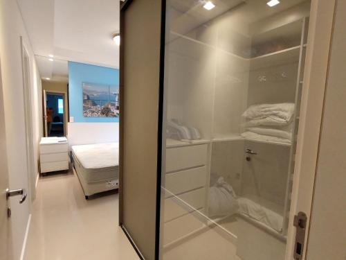 1 dormitorio con vestidor y puerta de cristal en Lanai Apart Hotel, Flat Moderno com Vista Mar no Posto 2 da Barra B1-0031, en Río de Janeiro