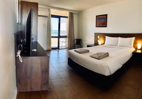 a bedroom with a bed and a television and a balcony at Hedland Hotel in Port Hedland