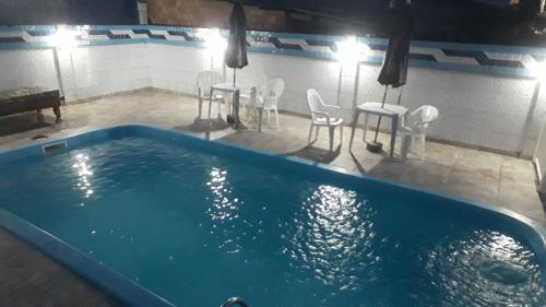 a large swimming pool with chairs and a table and a table and chairs at POUSADA CHALEIRA PRETA - Hospedagem & Conveniência in Arroio do Silva