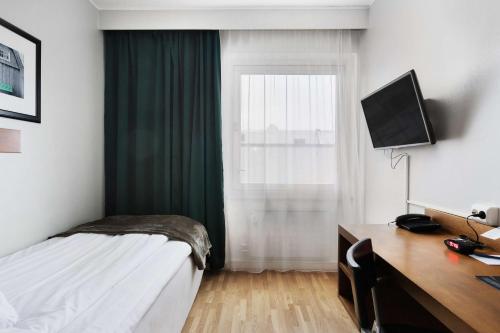 a bedroom with a bed and a desk and a window at Best Western Plaza Hotel in Eskilstuna