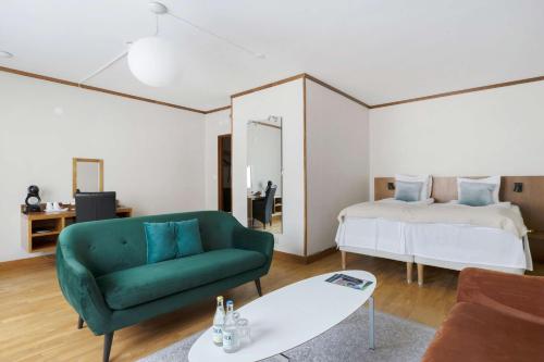 a living room with a green couch and a bed at Best Western Plaza Hotel in Eskilstuna