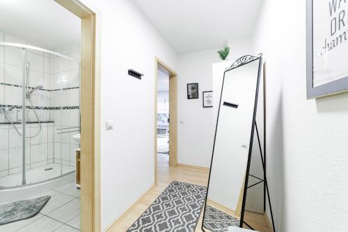 een badkamer met een spiegel naast een douche bij DEHOME - Laguna - Stay by Central Station in Koblenz