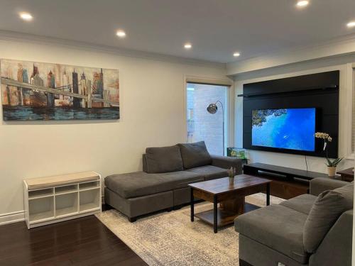ein Wohnzimmer mit einem Sofa und einem Flachbild-TV in der Unterkunft Modern main floor 3-bedroom apartment backing onto a park in Mississauga