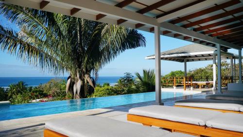 a villa with a swimming pool with a view of the ocean at Salvatierra Beachfront Hotel in Puerto Coyote