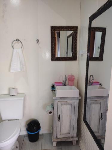 a bathroom with a toilet and two sinks and a mirror at Caminho das Dunas - Studios próx Praia do Rosa e Ouvidor in Praia do Rosa