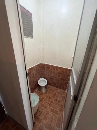 a bathroom with a toilet and a tiled floor at Yna's Place- The Third House in Lipa