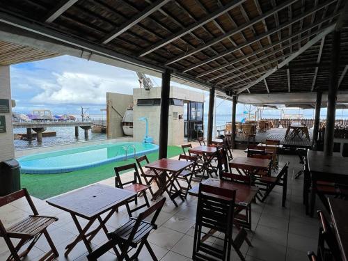 um restaurante com mesas e cadeiras e uma piscina em Victória Marina Flat em Salvador