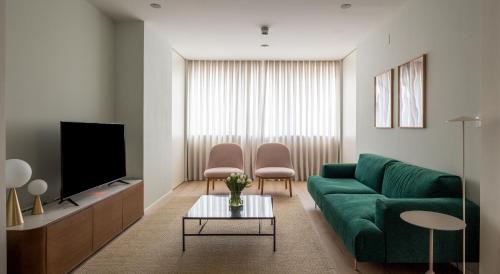 a living room with a green couch and a tv at The Passage Apartments in San Sebastián