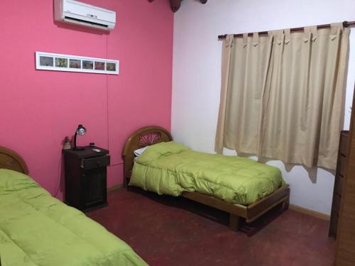 2 camas en una habitación de color rosa y verde en Solares de Cacheuta en Cacheuta