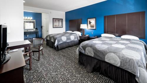 Una habitación de hotel con dos camas y un escritorio. en Belmont Inn and Suites Tatum, en Tatum