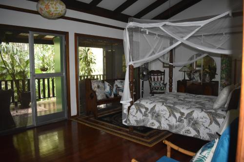 1 dormitorio con cama con dosel y porche en Oskar's Rain Forest Retreat, en Nelly Bay